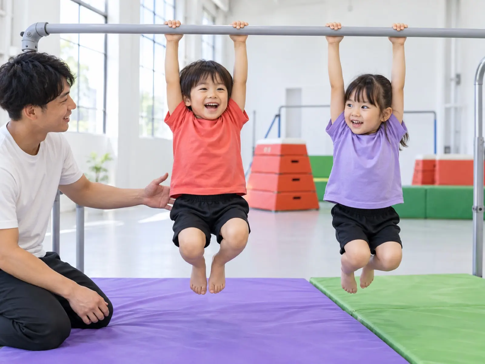 鉄棒にぶら下がる2人と、しゃがんで支える先生